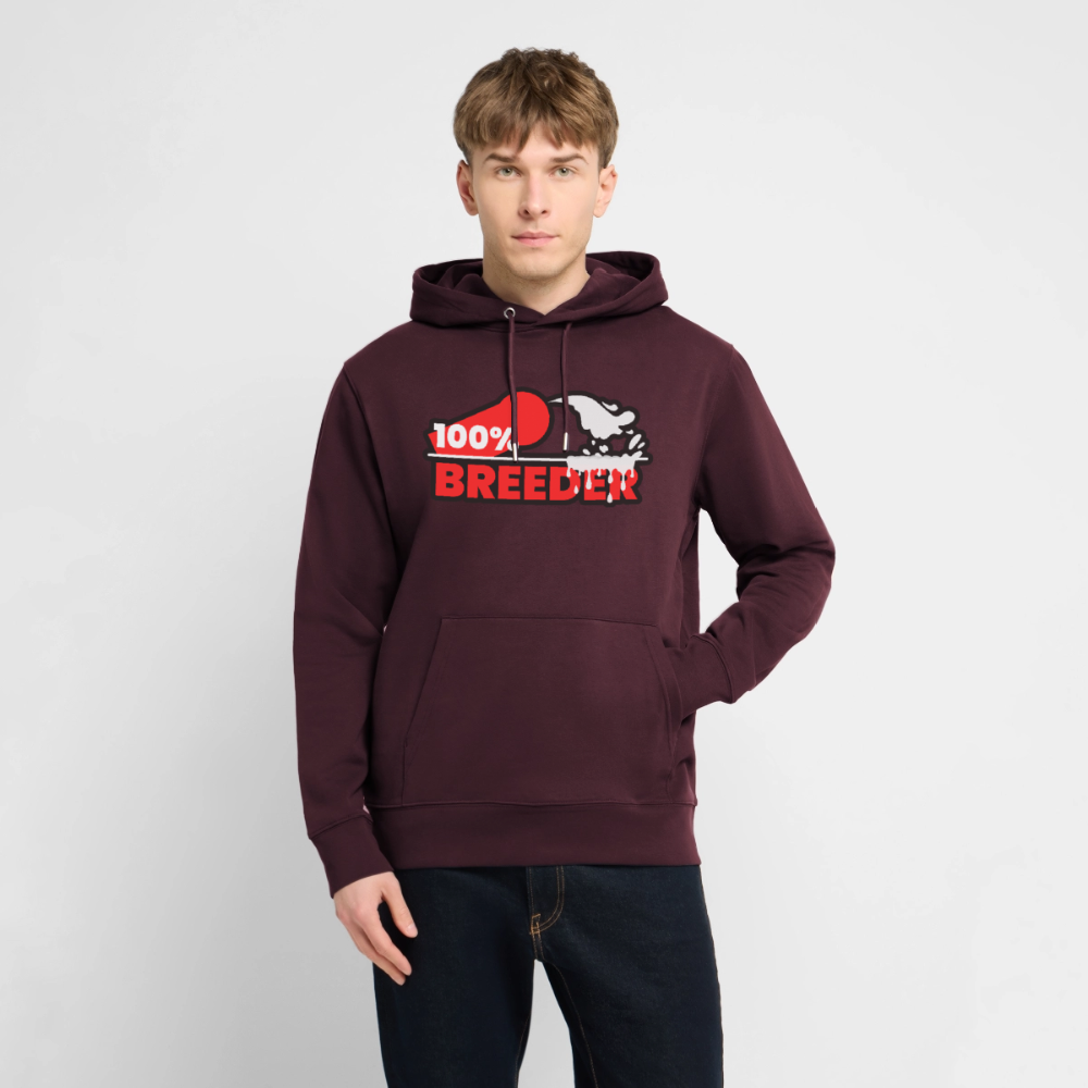 Junger Mann trägt maroonfarbenes Bio-Hoodie mit dem starken "100% Breeder" Kink Fetish Design – selbstbewusstes Top Statement für die Fetisch und Puppy Szene