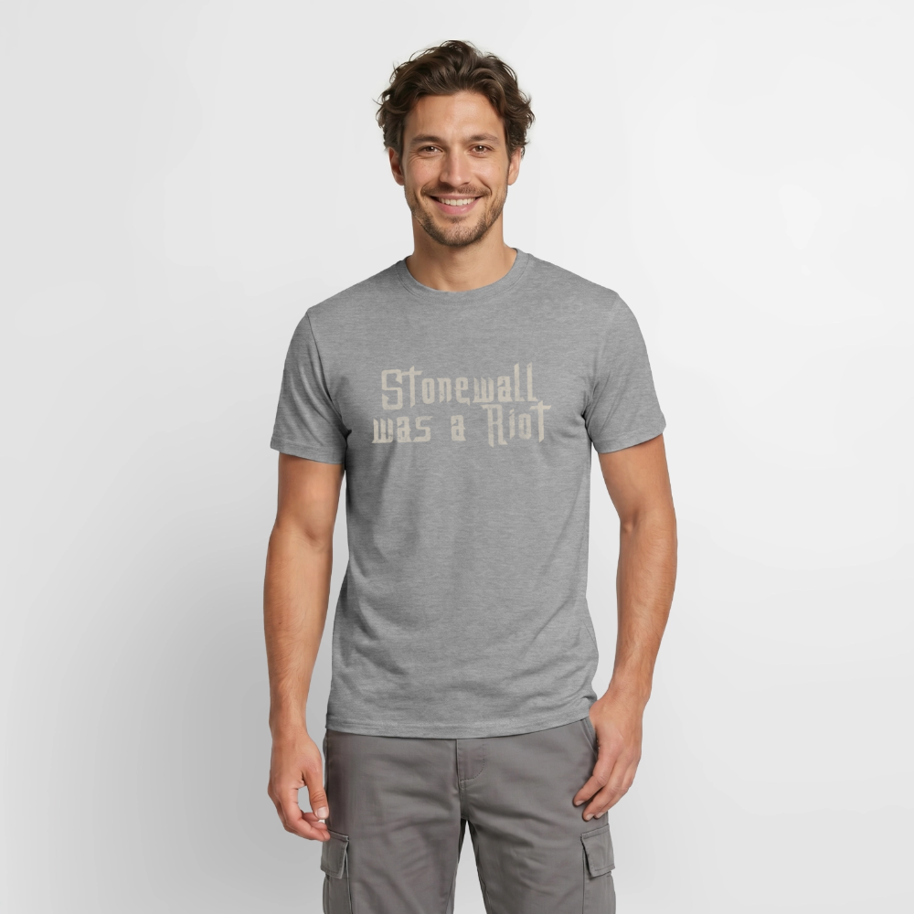 Ein Model trägt das graphit-melierte Shirt mit dem „Stonewall was a Riot“ Print. Die Kombination aus meliertem Stoff und rauer Stencil-Schrift sorgt für einen authentischen Street-Art-Look.