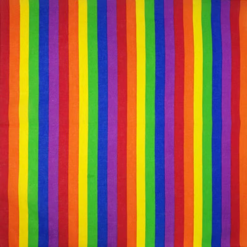Flach ausgebreitetes, quadratisches Bandana aus weicher Baumwolle. Das Pride-Accessoire zeigt sieben leuchtende, breite Regenbogenstreifen in Rot, Orange, Gelb, Grün, Dunkelblau, Violett und Pink, die vertikal über den gesamten Stoff verlaufen.