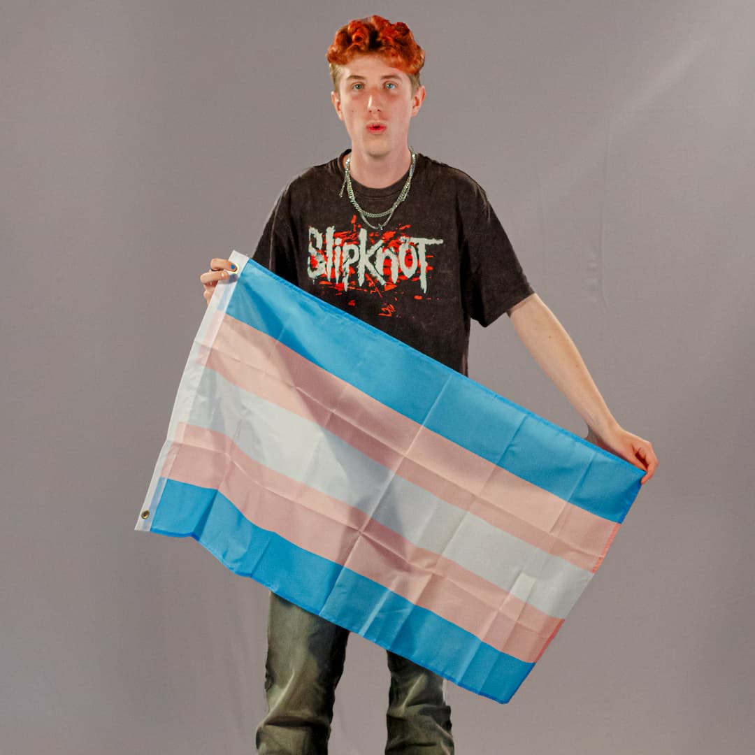 Justus Kornmesser, einer der Initiatoren von PrideLAB, präsentiert die kleine Trans-Pride-Flagge in 90x60 cm. Die Farben Hellblau, Rosa und Weiß des robusten Polyester-Stoffs sind klar erkennbar.