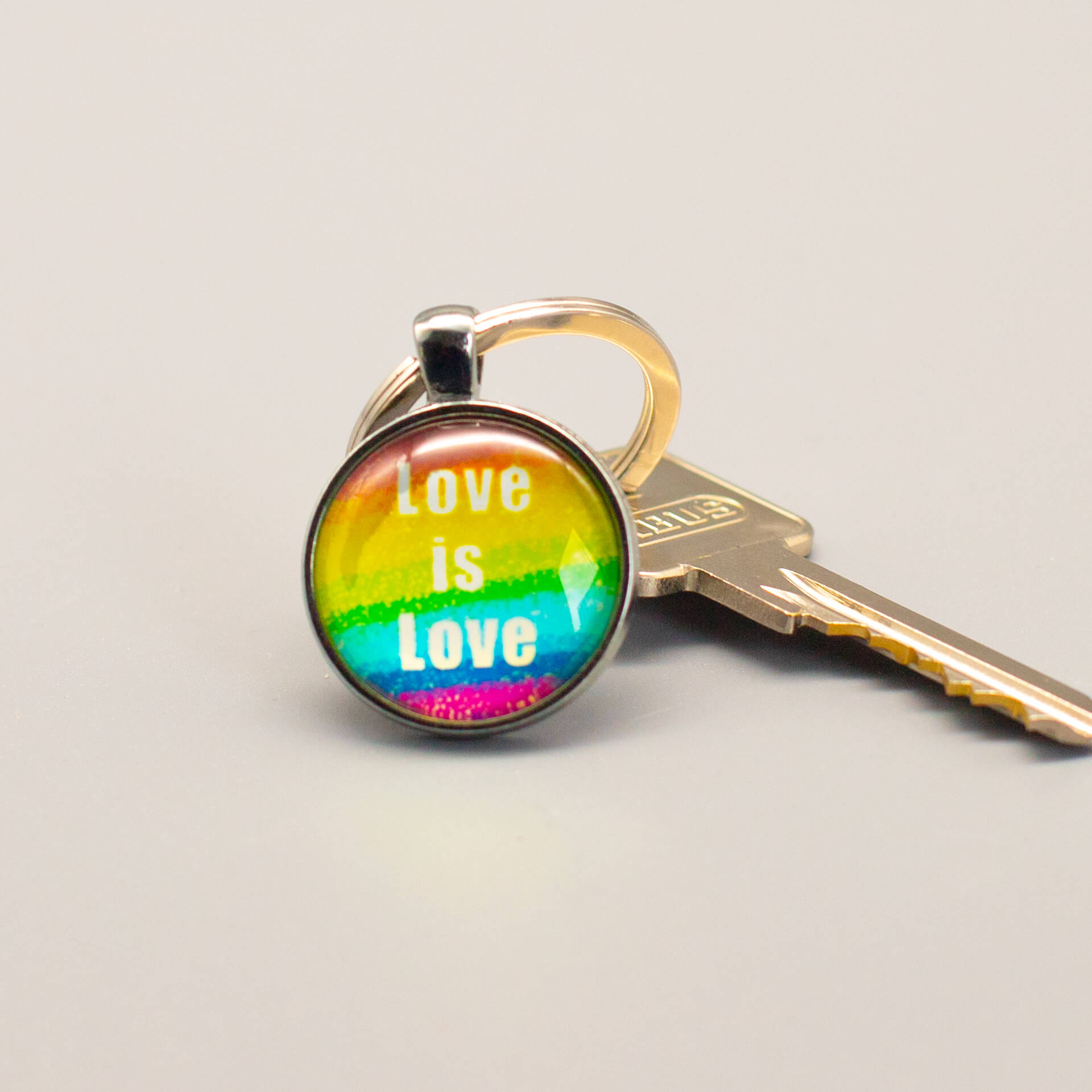 Dekorativer Pride Schlüsselanhänger mit der klaren Botschaft "Love is Love" auf Regenbogenfarben, alltagstauglich befestigt an einem Schlüssel.