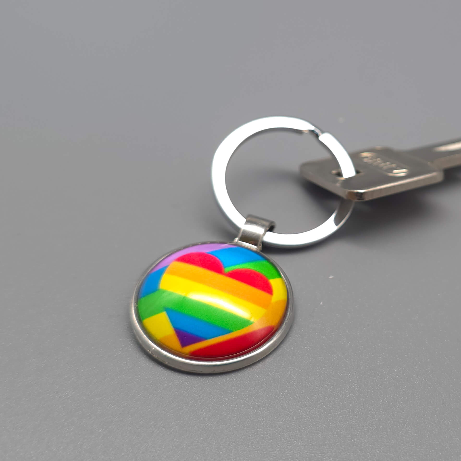 Regenbogen Herz Pride Schlüsselanhänger in Silber mit gewölbtem Glasdom, befestigt an einem Schlüssel als alltagstaugliches LGBTQ Accessoire