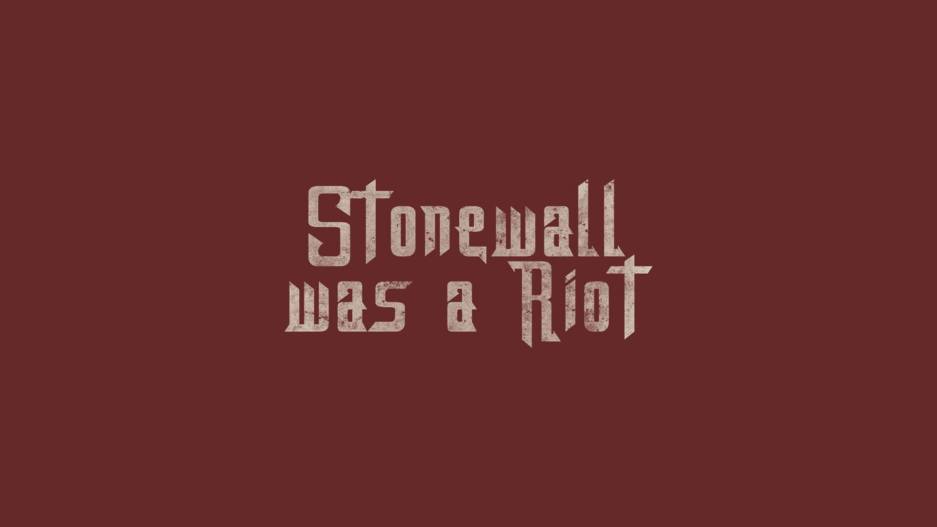 Zentrierter Schriftzug „Stonewall Was A Riot“ in gebrochener, rau wirkender Typografie auf dunkelrotem Hintergrund. Die hellbeigen, leicht verwitterten Buchstaben erinnern an historische Protestplakate und verweisen auf die Stonewall-Aufstände von 1969 sowie den Ursprung der LGBTIQ-Pride-Bewegung.