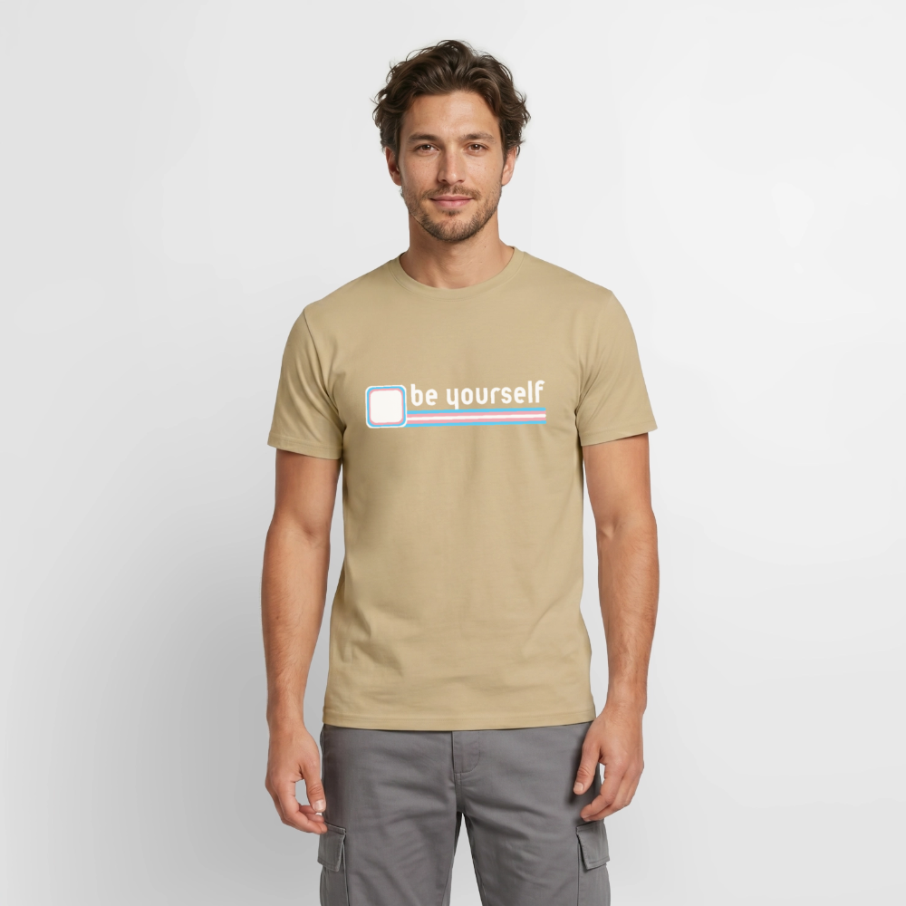 Ein männliches Model trägt das sandbeige T-Shirt mit dem minimalistischen Trans-Pride-Motiv. Die Kombination aus reduziertem Text und den Trans-Linien zeigt: Echte Selbstbehauptung braucht keine lauten Grafiken.