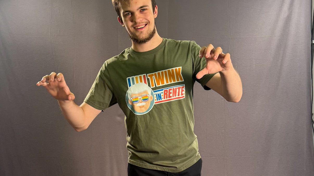 Leo präsentiert freudig und frech das „Twink in Rente“ T-Shirt von PrideLAB. Humorvolles queeres Statement-Shirt mit einem grauhaarigen Opa mit Regenbogen-Sonnenbrille und dem großen Schriftzug „TWINK IN RENTE“. Satire auf den Jugendwahn in der schwulen Szene.